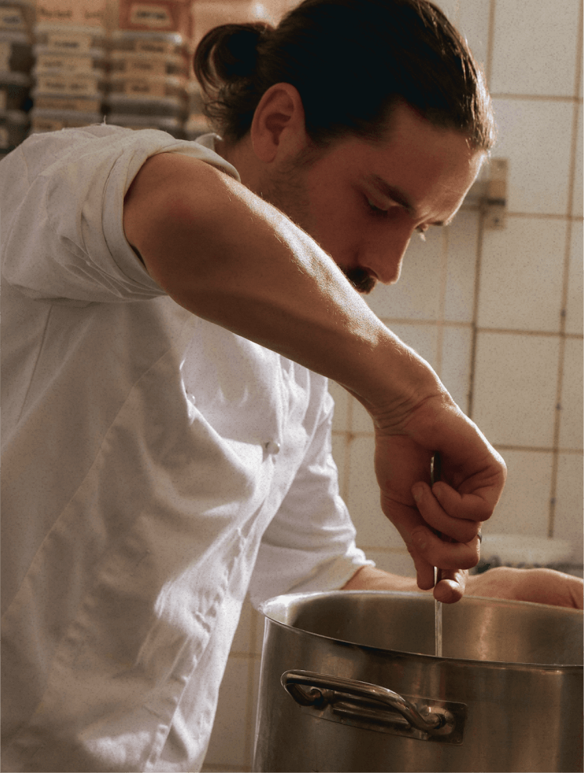 male chef in a kitchen stirring a pot